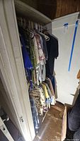 Full view of clothing hanging in closet including Hawaiian shirts, plaid shirts, long and short sleeved shirts, and jacket