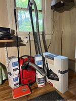 Full lot contents showing red Miele Titan vacuum, Electro Plus box, multiple AirClean filter boxes, vacuum hoses and attachments