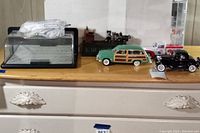 Wide shot of lot items including model cars, convertible tops, and mechanical cat and mouse toy on dresser