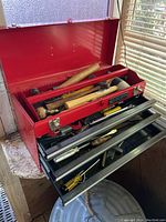 Top view of tool box upper compartment with wooden handles and various tools visible