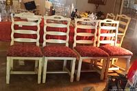 Full view of all four vintage Monterey-style dining chairs lined up, showing cream wooden frames and red upholstered seats.
