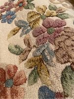 Close-up of a cream wool rug with colorful floral pattern showing the plush texture and design details.