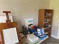 Overall view of easel, canvases and supplies on table