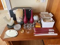 Wide view of candles, candle holders, glass coasters, and boxes on wooden surface.