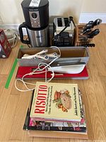 Photo showing coffee maker, toaster, knife set, oven mitts, and cookbooks on floor