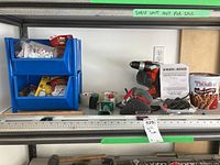 Photo showing shelf with Black and Decker drill, Skil drill, battery pack, instruction manual, wire brush, level, and blue storage bins with hardware supplies