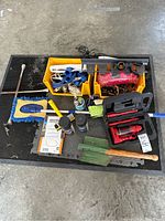 Overview of all items included in the lot arranged on a black rubber mat in a garage floor.