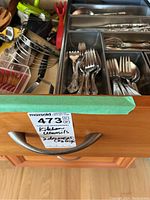 Top drawer showing cutlery organized in metal tray with forks and spoons.