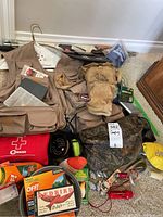 Full lot view showing fishing vest, first aid kit, fishing reels, insect repellent, and rain poncho.