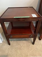 Front view of the mahogany side table showing drawer and open shelf.