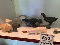 Shelf view showing four soapstone animal carvings, a flint rock and a wood duck figure