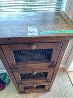 Front view of wood storage stand showing three compartments with wire mesh doors and wooden knobs.