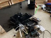 Samsung 38 inch flat screen TV with DVDs and tangled electronics on carpeted floor