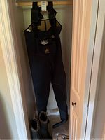 Full view of black neoprene wader hanging with boots below