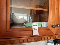 Lenox dishes with carved floral pattern inside a wooden cabinet.