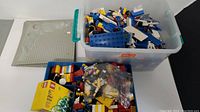Two plastic bins filled with assorted LEGO bricks and pieces showing variety and quantity present.