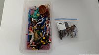 Plastic bin with loose toy figures including Batman and Robin among others