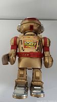 Front view of Walking Talking Toby Robot Toy showing gold, red, and silver details, with the toy standing upright.