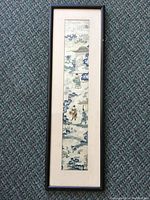 Full view of the framed antique Chinese embroidery piece showing elongated vertical shape with matting and black frame.