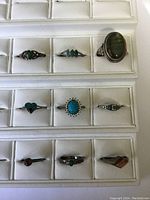 Group of ten sterling silver rings displayed on white jewelry tray, showing variety of stones and styles