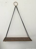 Front view of hanging shelf showing wood platform and four metal rods attached to circular ring.