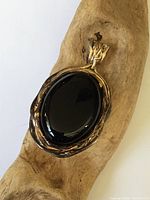 Close-up front view of large oval black onyx set in sterling silver with gilt wash pendant, showing wear on gilding.