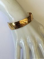 Cuff bracelet displayed on white mannequin hand showing full engraved outer surface.