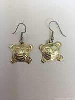 Pair of sterling silver earrings shown front view on white background with detailed Native art sun faces.