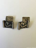 Front view of pair of vintage sterling silver cufflinks with abstract swirl design on hammered rectangular base