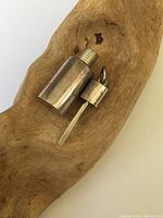 Pendant resting on wood background showing bottle and screw cap with attached stir stick.