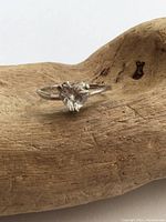Front close-up of sterling silver ring with heart-shaped clear crystal on wooden display, showing tarnish on band.