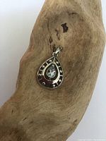 Front view of teardrop sterling silver pendant with blue topaz on wooden background