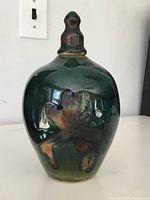 Front view of the pottery lidded vase showing glazed finish and floral relief design.