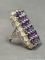 Side and partial top view of the silver ring with multiple oval amethyst stones arranged in rows with scalloped edges.
