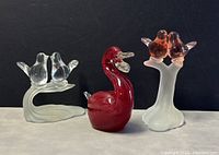 Front view of the three art glass bird figurines showing red swan in center and frosted bird pairs on sides.