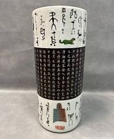 Front view of Chinese porcelain vase showing hand painted black script pictograms and a central black panel with dense Chinese characters including a green mythical creature.