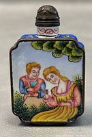 Front side of snuff bottle showing woman in yellow dress and man in blue with pink scarf by trees.