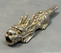 Close-up of dragon head shaped pipe mouthpiece showing detailed facial carving and open mouth for smoking.