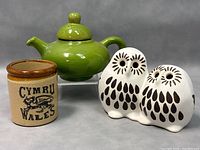 Photo of green ceramic teapot, double owl ceramic figurine, and small ceramic pot