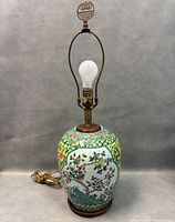 Front view of the hand painted porcelain vase table lamp showing the floral and bird motifs, bulb socket, and wooden base.