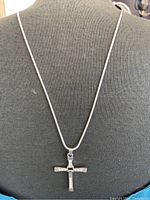 Front view of the necklace worn on a display bust showing the cross pendant and chain.
