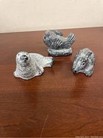 Set of 3 small animal sculptures on a wooden surface including a soapstone seal and fish figurine