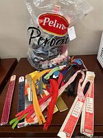 Image showing a clear plastic bag containing loose zippers in various colors including blue, pink, red, yellow, orange, grey and brown, laid out on a surface with some zippers still in packaging.