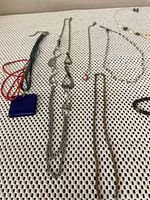 Photo showing multiple necklaces and bracelets arranged on fabric surface with various designs and colors.