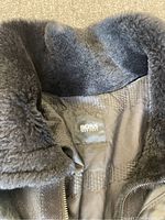 Close-up of the coat's inner label showing 'BOSS HUGO BOSS' branding and plush fur collar lining.