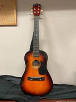 Full view of a small-sized Nova acoustic guitar with sunburst finish, showing strings, fretboard, and headstock.