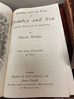 Opened title page of Dickens' 'Dombey and Son' showing publisher information including Chapman & Hall and Henry Frowde.