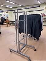Full metal clothing rack with four adjustable arms and caster wheels in an indoor environment