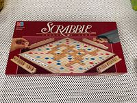 Scrabble game box with branding and overlay image of game play