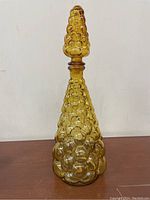 Full view of the amber glass decanter shaped like a grape cluster with matching stopper on top.